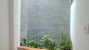 Un coin agrémenté d’un jardin intégré où poussent des plantes vertes, d’un banc en bois et d’un mur en pierre.