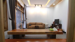 Un salon moderne avec une table à manger en bois, un canapé, un téléviseur et un petit coin cuisine.