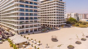 A modern multi-story hotel with a curved facade, outdoor seating area, and a sandy courtyard. - Sea On (Navodari)