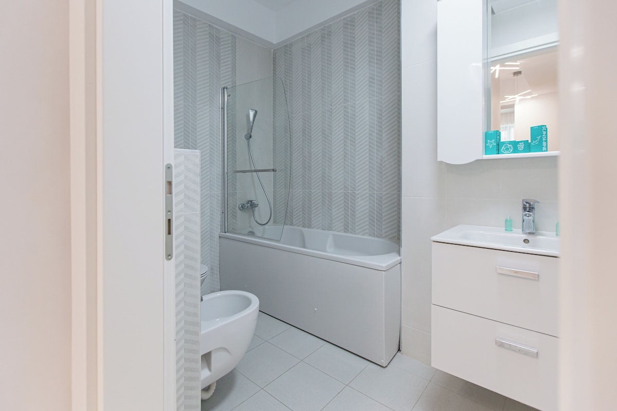 A modern bathroom with a shower, toilet, and sink.