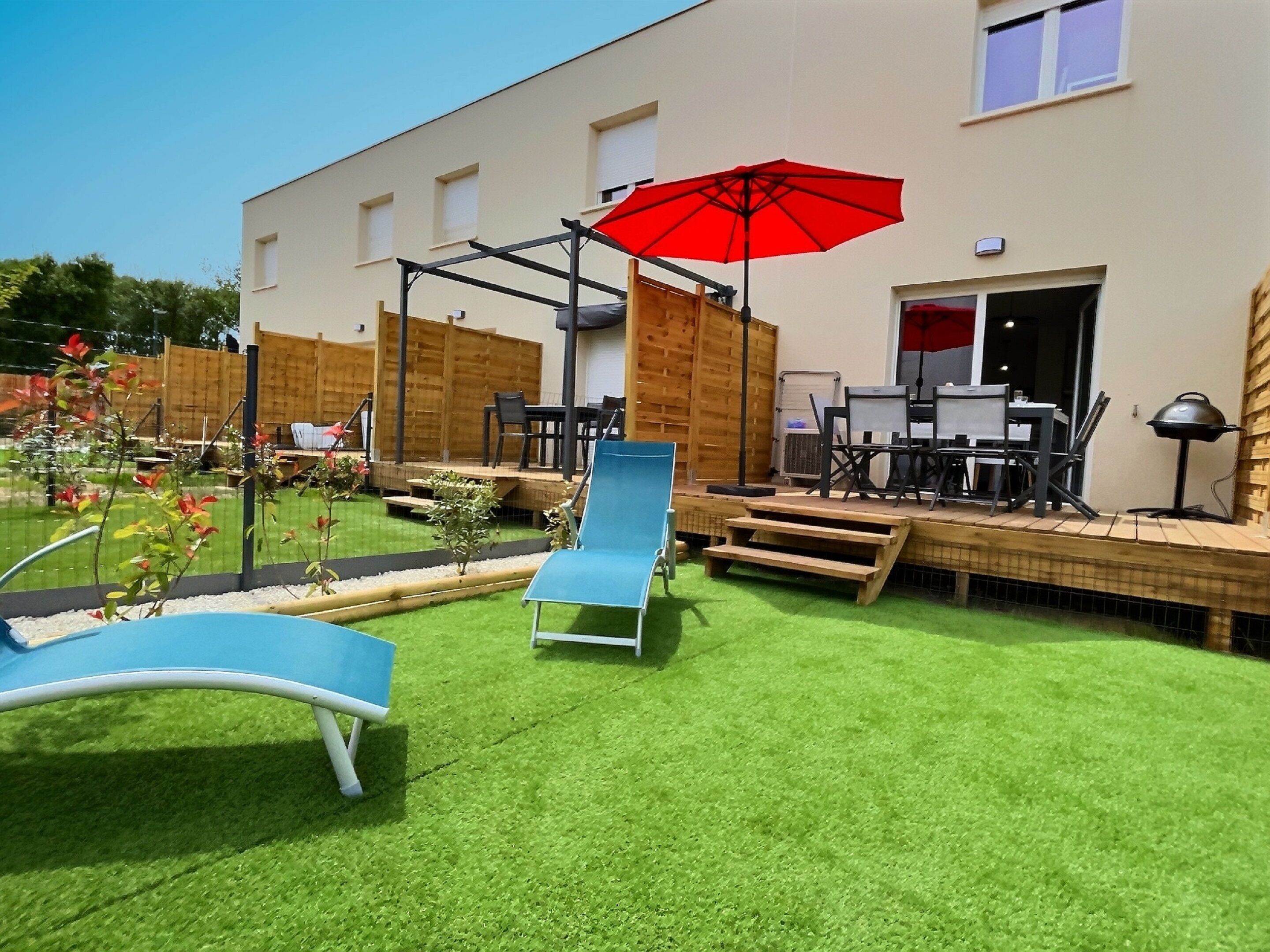 Patio esterno moderno con tavolo da biliardo, poltrone relax e un ombrellone rosso.