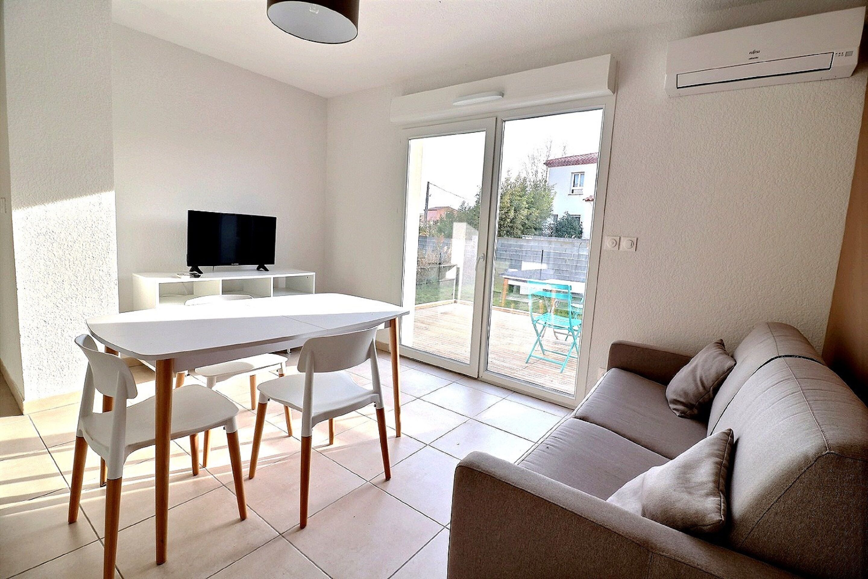 A modern living space with a dining area, a sofa, and a television.