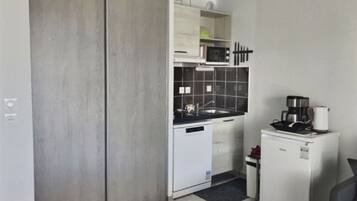 Eine kleine Küche mit Mikrowelle, Spüle und Kaffeemaschine.