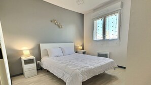 Un dormitorio con cama, mesitas de noche, un reloj de pared y una ventana con cortinas.