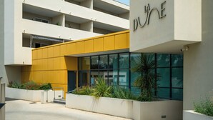 Un edificio moderno con fachada amarilla y el nombre "LA DUNE" en la parte lateral.