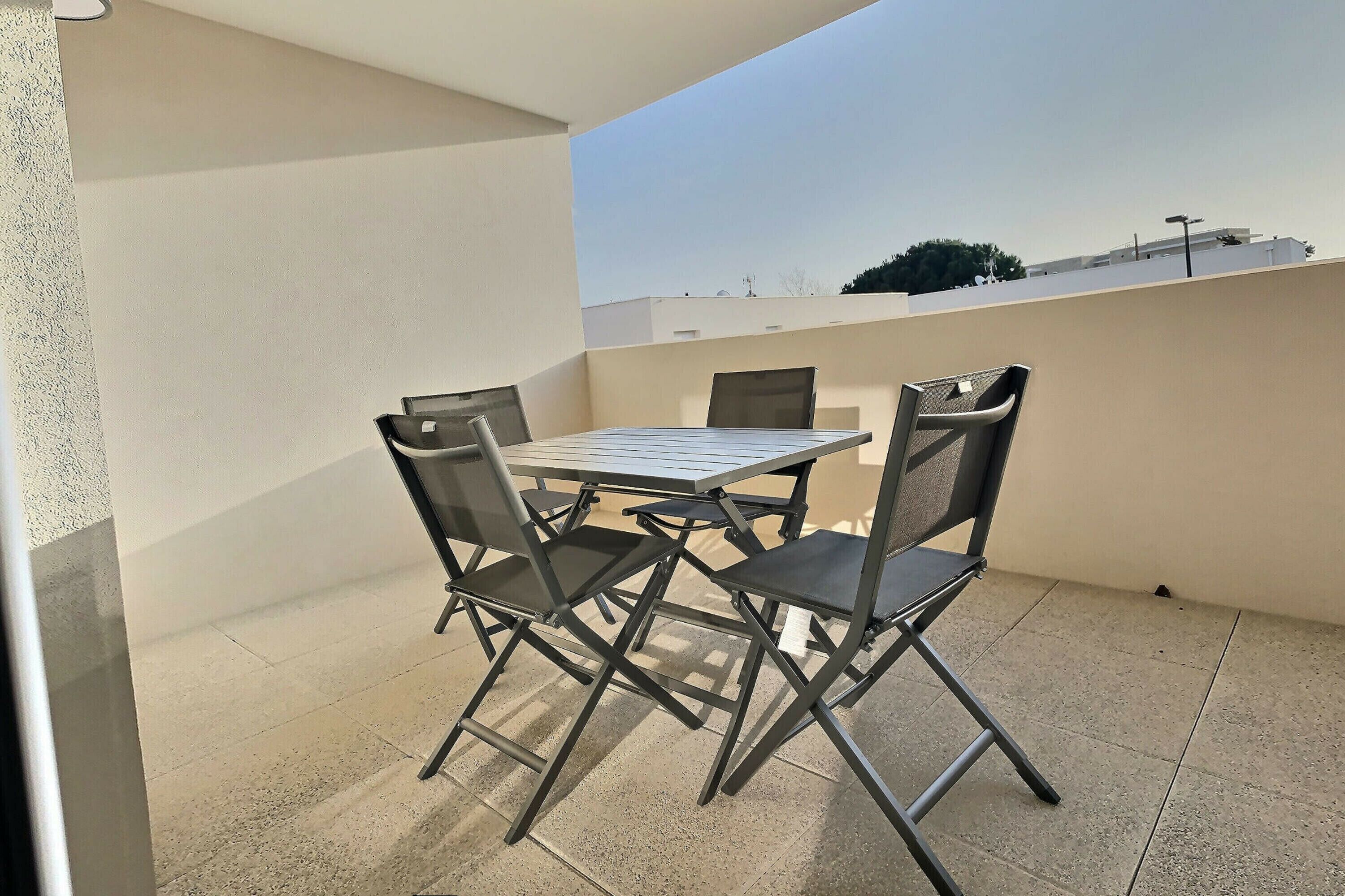 Un balcon avec une table et quatre chaises.