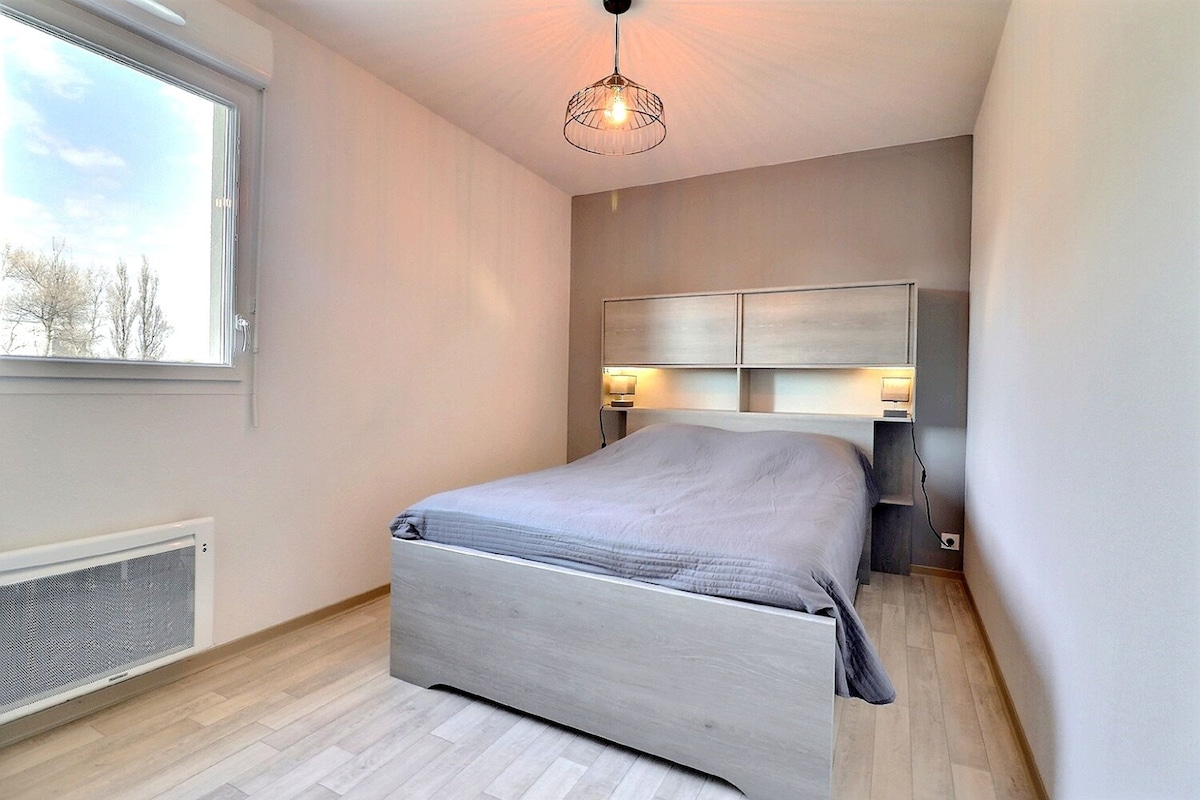 A bedroom with a bed, a window, a radiator, and a ceiling light.
