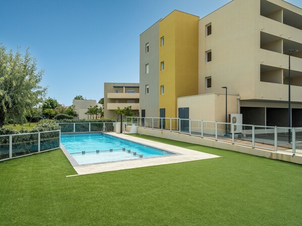 Um edifício moderno com piscina cercada por grama sintética.