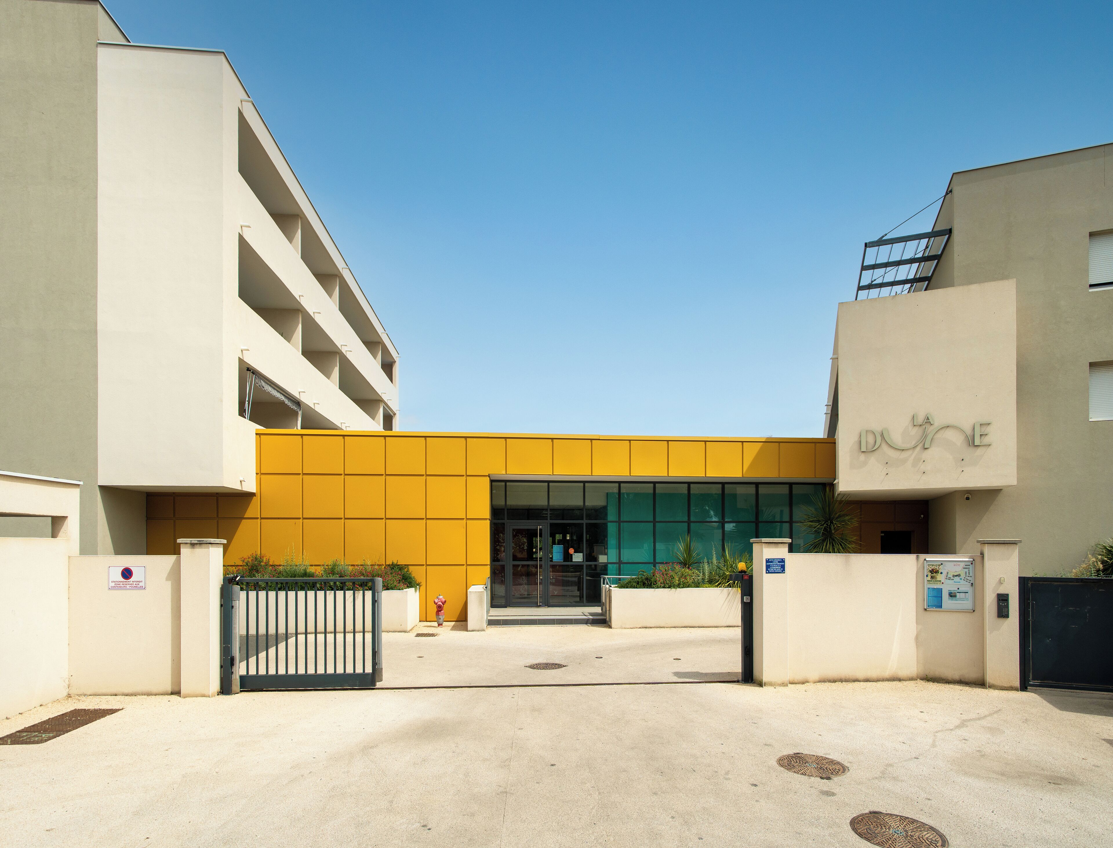 A building with a yellow facade and a sign reading "LA DUNE".
