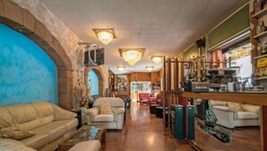 A cozy lounge area with leather sofas, a coffee bar, and a stone wall. - Albergo Ristorante Stella (Palestrina)