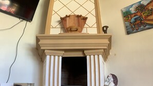 A fireplace with a decorative mantel, a mounted television, and a painting on the wall.