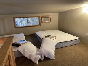 A small, compact room with two single beds, a window, and an air conditioning unit. - Royal Gate Retreat Unit 4 (New Braunfels)