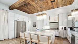 A modern kitchen with white cabinetry, a stainless steel refrigerator, a large island with stools, and pendant lighting. - Coastal Dream|Short Walk to Beach Access|Private Pool|Gulf Views|Golf Cart (Santa Rosa Beach)