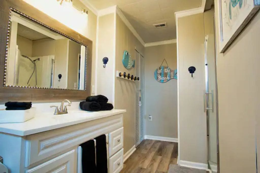 A bathroom with a large mirror, a sink, and a towel rack.