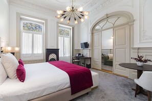 Habitació d'hotel amb un llit gran, un escriptori, una televisió i una zona de seients.