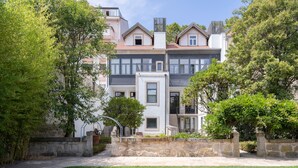 Un immeuble résidentiel à plusieurs étages, doté d’une façade en pierre, d’une entrée centrale et d’une pelouse bien entretenue.