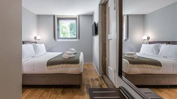 Une chambre d’hôtel avec deux lits, une fenêtre, une télévision et un miroir.