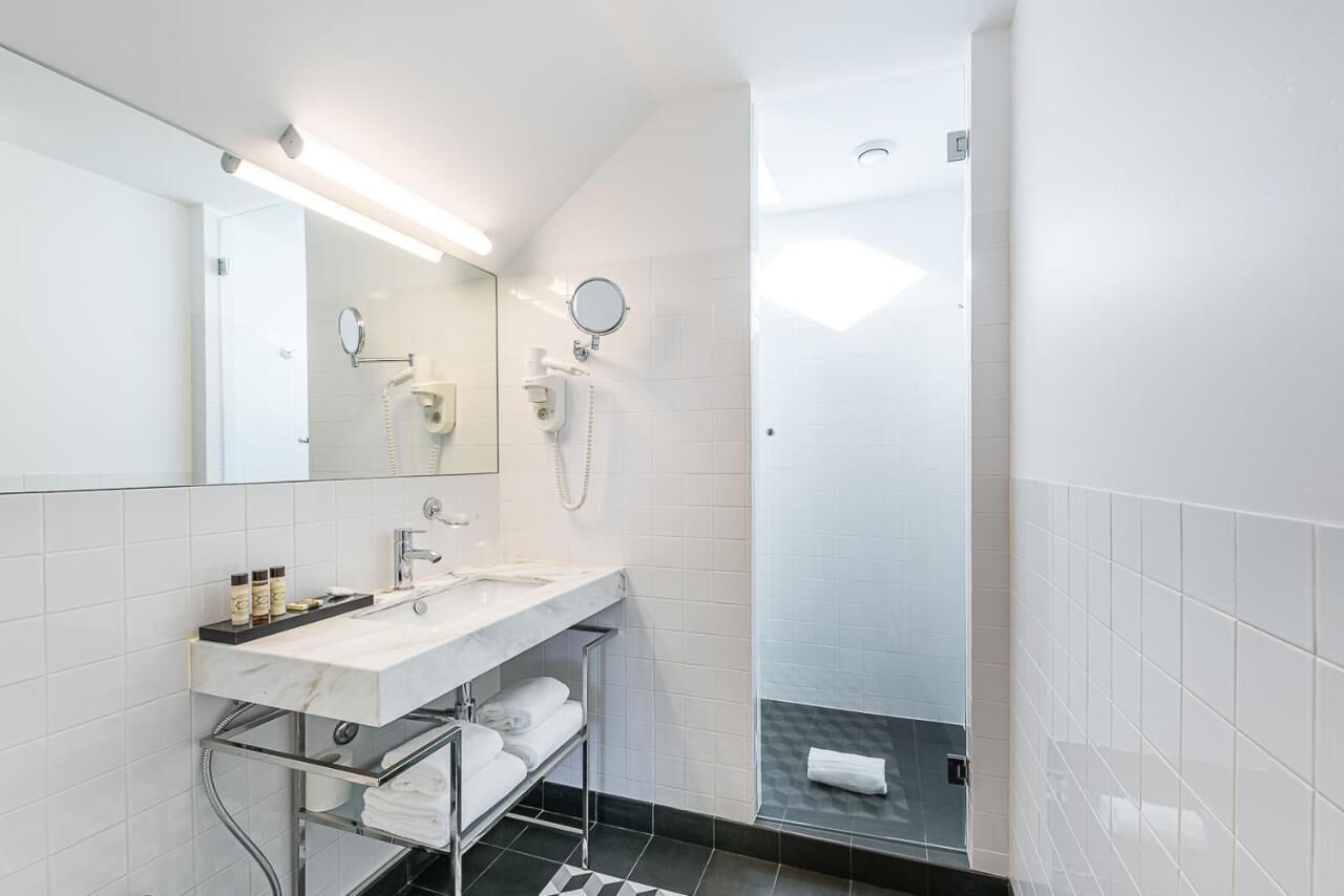A modern bathroom with a white sink, mirror, and towel rack.
