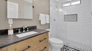 Un baño moderno con un espejo grande, un lavamanos y un inodoro.