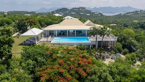 A large house with a swimming pool, surrounded by lush greenery and mountains in the background. - Callisto (2/3 Rooms) Luxury villa (Les Terres Basses)