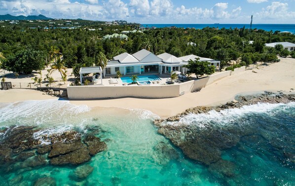 Ein Strandgrundstück mit Schwimmbad, überdachter Terrasse und Meerblick.