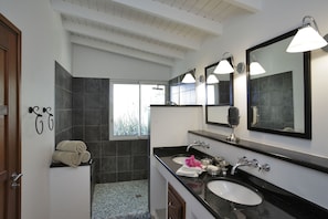 Une salle de bain moderne avec deux lavabos, un grand miroir et un espace douche.