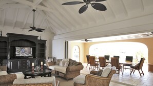 A spacious living area with wicker furniture, a fireplace, and a television.