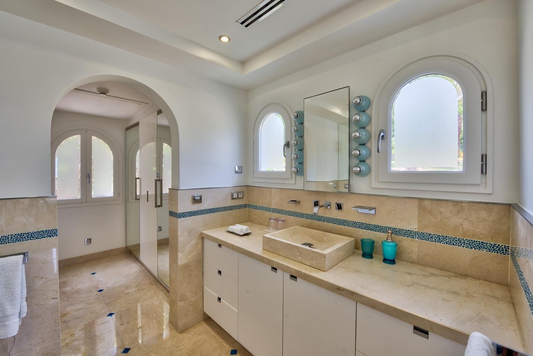 A modern bathroom with a large vanity, two mirrors, and a tiled backsplash.