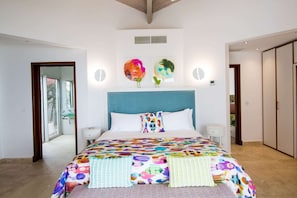 Ein Schlafzimmer mit einem großen Bett, einem Nachttisch, einer an der Wand befestigten Uhr und einer Tür zu einem weiteren Raum.
