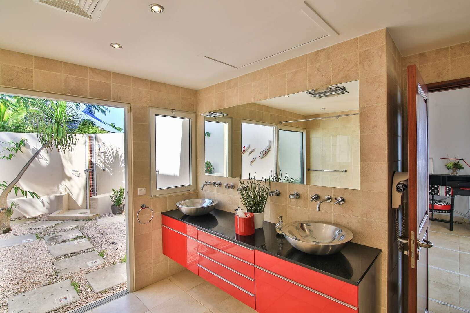 Ein modernes Badezimmer mit einem großen Spiegel, zwei Waschbecken und einer roten Waschtischkommode.