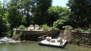 A floating platform with seating and a staircase leading to a garden area surrounded by trees. - Romantic suite with private jacuzzi 1 hour from Paris (Vendières)