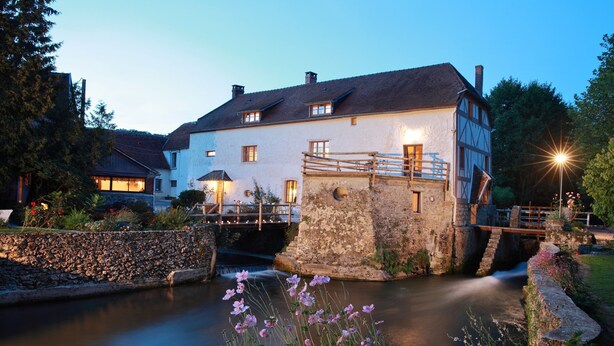 A historic building with a stone bridge over a calm river, surrounded by lush greenery. - Romantic suite with private jacuzzi 1 hour from Paris (Vendières)