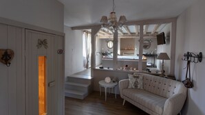 A cozy living room with a sofa, a small table, and a staircase leading to an upper level. - Romantic suite with private jacuzzi 1 hour from Paris (Vendières)