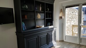 Quarto com um armário preto, uma TV de tela plana e vista para uma parede de pedra através de uma porta de vidro.
