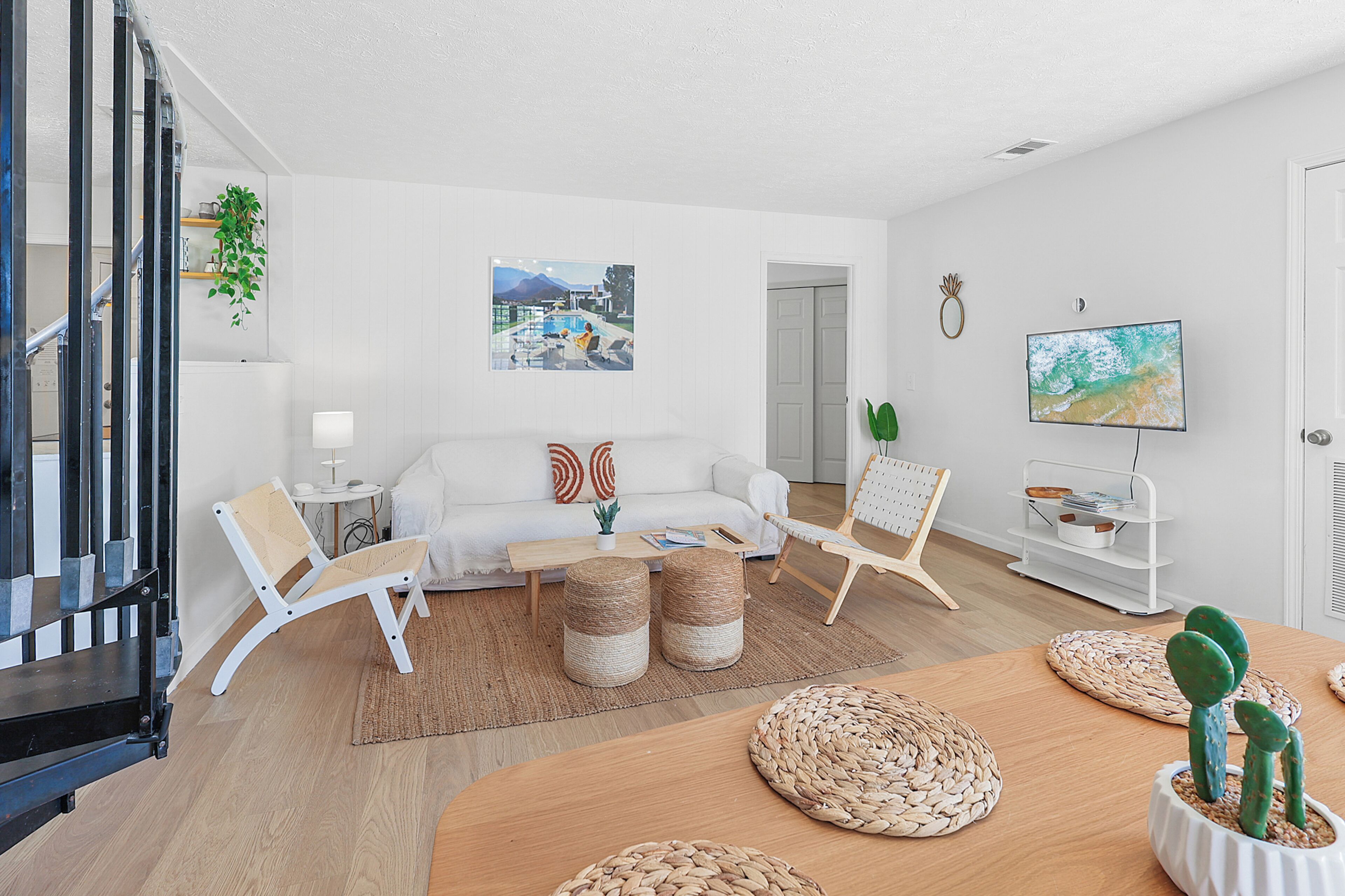 Ein modernes Wohnzimmer mit einer Couch, Sesseln, einem Couchtisch und einem Fernseher.