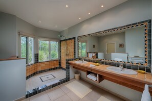 Un bagno moderno con due lavabi, un ampio specchio e una cabina doccia.