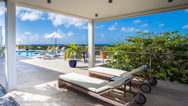 A balcony with lounge chairs, a pool, and a view of the ocean. - Oceane (2/4 Rooms) Luxury villa (Marigot)