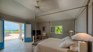 A bedroom with a bed, a TV, a desk, and a balcony with chairs. - Oceane (2/4 Rooms) Luxury villa (Marigot)