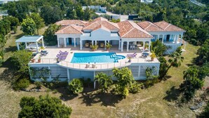 A large house with a swimming pool, multiple lounge chairs, and a covered patio area. - Beautiful Oceane Luxury villa (Marigot)