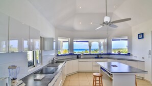 A modern kitchen with a large island, a built-in oven, and a view of the ocean. - Beautiful Oceane Luxury villa (Marigot)