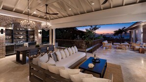 Un'ampia zona relax esterna dal design moderno, con un divano grande, tavolo da pranzo e diverse opzioni di seduta.