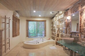A bathroom with a stone wall, a bathtub, a glass sink, and a window with blinds. - Landmark (4/6 Rooms) Luxury house (Holetown)