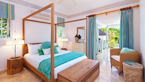 A spacious bedroom with a four-poster bed, a wooden bench, wicker furniture, and a view of a lush garden through a glass door. - Moon Dance Luxury villa (Sandy Lane)
