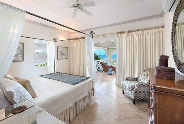 A bedroom with a bed, a chair, a table, and a view of the outdoors.