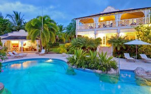 A pool area with lounge chairs and a building with a balcony. - Calliaqua (3/5 Rooms) (Mount Standfast)