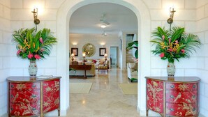 A hallway with a white brick wall, a ceiling fan, and a dining area with a round mirror and a chandelier.