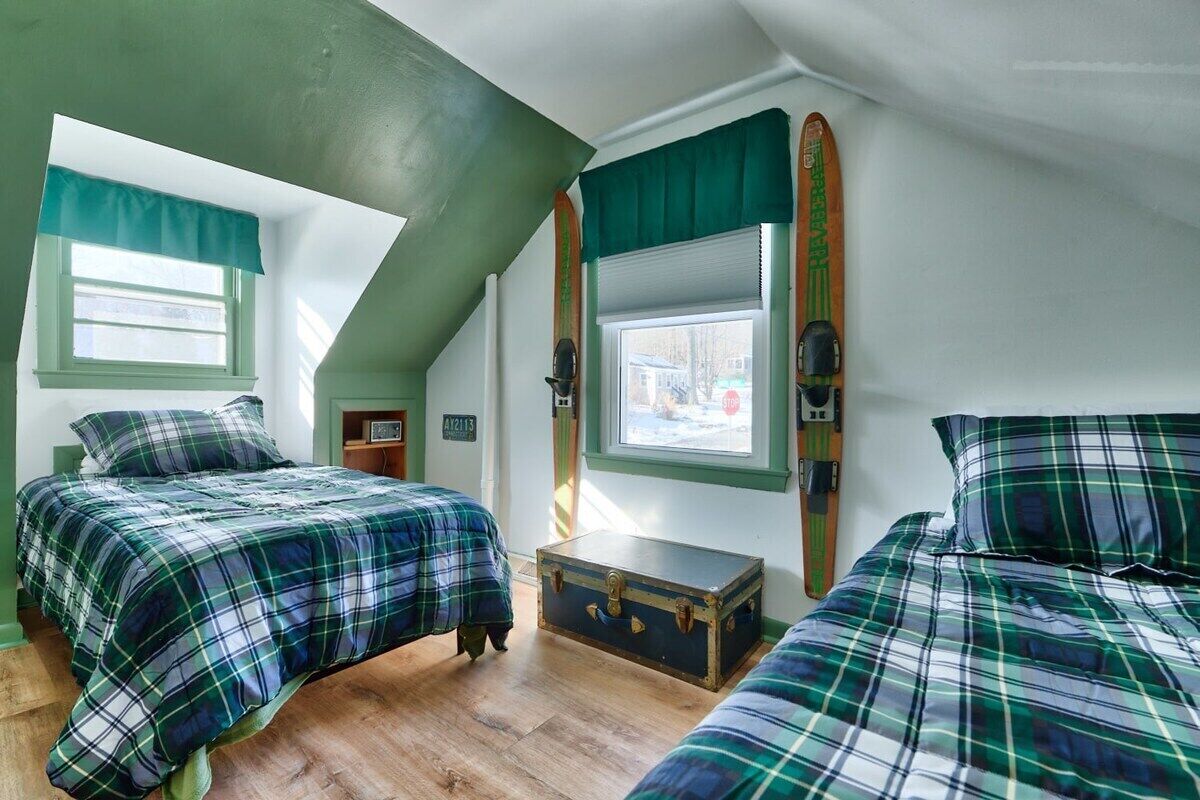 Een kamer met twee bedden, een raam, een ski en een kleine dressoir.