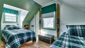 Een kamer met twee bedden, een raam, een ski en een kleine dressoir.