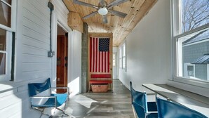 A hallway with wooden ceiling and walls, a large American flag, and blue chairs along the sides. - Lakefront - King - W&D - PetsOK - Kayaks - SUPs (Coventry)