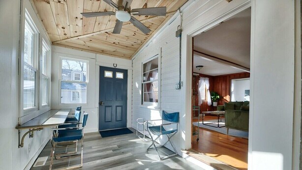 A room with a wooden ceiling, a ceiling fan, a blue door, and a dining area with a table and chairs. - Lakefront - King - W&D - PetsOK - Kayaks - SUPs (Coventry)